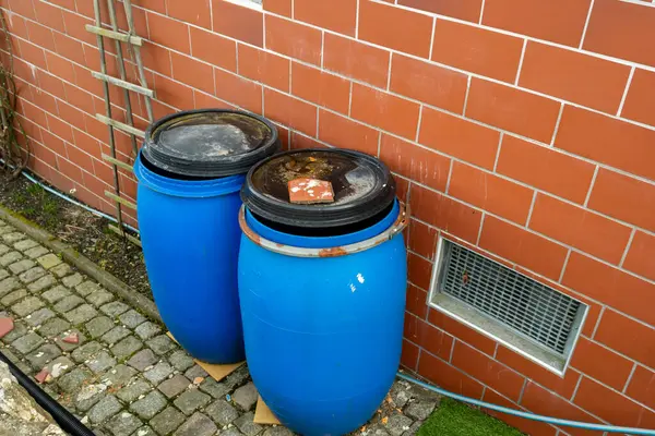 old blue plastic barrel for rainwater in the garden