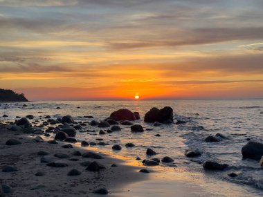 sunset on the beach with rocks on the baltic sea, island Ruegen in Germany Cap Arkona clipart