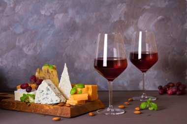 Bardaklar ve bir şişe kırmızı şarap ve şarap aperatifler peynir, ekmek ve fındık kahverengi ahşap zemin üzerinde fotokopi alanı ile