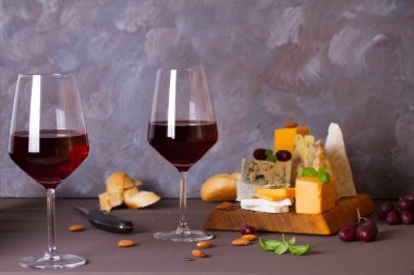 Bardaklar ve bir şişe kırmızı şarap ve şarap aperatifler peynir, ekmek ve fındık kahverengi ahşap zemin üzerinde fotokopi alanı ile