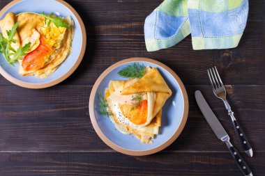 Doldurulmuş ince krep füme somon, krem peynir ve çırpılmış yumurta ve somon. Mavi tabakta krep. Yukarıdan görüntüle, en üstten