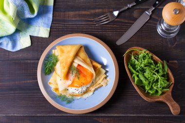 Doldurulmuş ince krep füme somon, krem peynir ve çırpılmış yumurta ve somon. Mavi tabakta krep. Yukarıdan görüntüle, en üstten