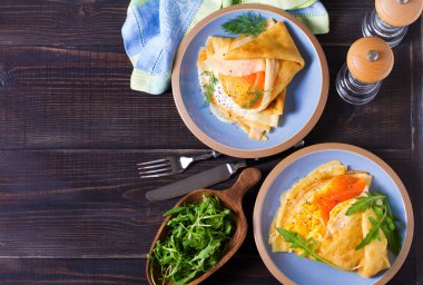 Doldurulmuş ince krep füme somon, krem peynir ve çırpılmış yumurta ve somon. Mavi tabakta krep. Yukarıdan görüntüle, en üstten