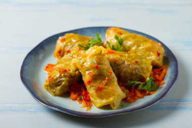 Lahana dolması. Lahana ambalajı ya da rulo. Chou farci, dolma, sarma, golubtsy veya golabki mavi tabakta yeşil masada
