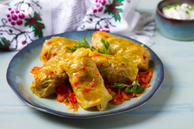 Lahana dolması. Lahana ambalajı ya da rulo. Chou farci, dolma, sarma, golubtsy veya golabki mavi tabakta yeşil masada