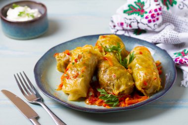 Lahana dolması. Lahana ambalajı ya da rulo. Chou farci, dolma, sarma, golubtsy veya golabki mavi tabakta yeşil masada
