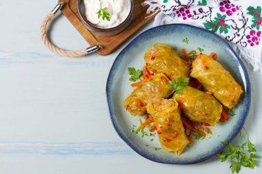 Stuffed cabbage leaves. Cabbage wraps or rolls. Chou farci, dolma, sarma, golubtsy or golabki on blue plate on green blue table. High angle view with copy space clipart