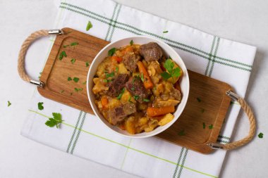 Beyaz arka planda beyaz bir kasede sebzeli leziz biftek güveci. Yüksek açı görünümü