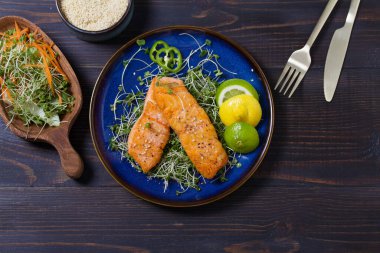 Izgara somon fileto, ahşap masada mavi tabakta mikro yeşillikler. Yüksek açı görünümü
