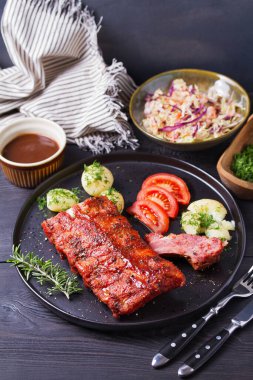 Siyah tabakta patates ve lahana salatası.
