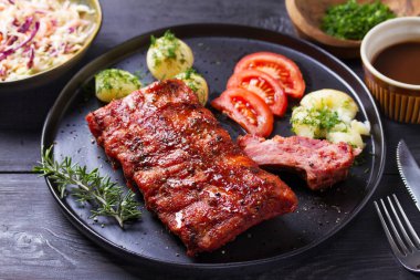 Siyah tabakta patates ve lahana salatası.