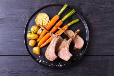 Kızarmış kuzu pirzolası. Siyah tabakta sebzeli kuzu pirzolası. Yukarıdan görüntüle, en üstten 