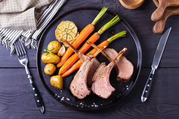 Kızarmış kuzu pirzolası. Siyah tabakta sebzeli kuzu pirzolası. Yukarıdan görüntüle, en üstten 