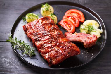 Izgara domuz pirzolası, haşlanmış patates, taze sebze, siyah arka plan.