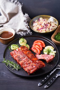 Izgara domuz pirzolası, haşlanmış patates, taze sebze, siyah arka plan.