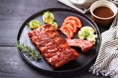 Izgara domuz pirzolası, haşlanmış patates, taze sebze, siyah arka plan.