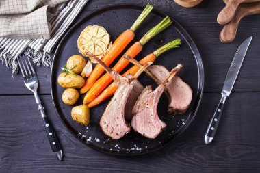 Havuçlu ve patatesli kuzu pirzola, siyah arka plan. Kızarmış kuzu pirzolası. Yüksek açı görünümü