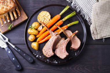 Havuçlu ve patatesli kuzu pirzola, siyah arka plan. Kızarmış kuzu pirzolası. Yüksek açı görünümü