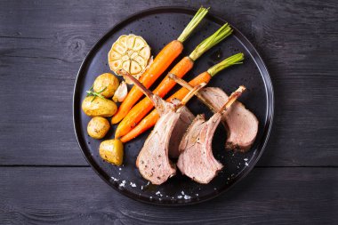 Havuçlu ve patatesli kuzu pirzola, siyah arka plan. Kızarmış kuzu pirzolası. Yüksek açı görünümü