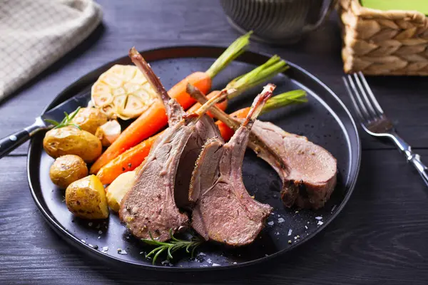 Havuçlu ve patatesli kuzu pirzola, siyah arka plan. Kızarmış kuzu pirzolası