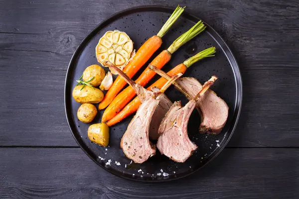 Havuçlu ve patatesli kuzu pirzola, siyah arka plan. Kızarmış kuzu pirzolası. Yüksek açı görünümü