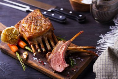 Kızarmış kuzu pirzolası. Servis panosunda kuzu pirzolası ve siyah ahşap arka planda