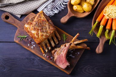 Kızarmış kuzu pirzolası. Servis panosunda kuzu pirzolası ve siyah ahşap arka plan. Yüksek açı görünümü