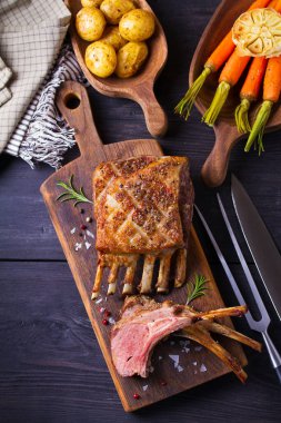 Kızarmış kuzu pirzolası. Servis panosunda kuzu pirzolası ve siyah ahşap arka plan. Yüksek açı görünümü