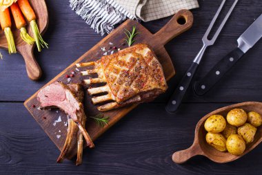 Kızarmış kuzu pirzolası. Servis panosunda kuzu pirzolası ve siyah ahşap arka plan. Yüksek açı görünümü