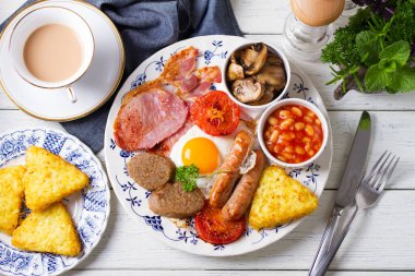 Sosis, domuz pastırması, puding, yumurtanın sarısı, patates kızartması, fasulye ve domatesli tam İrlanda kahvaltısı. Yukarıdan bak, en iyi stüdyo çekimi.
