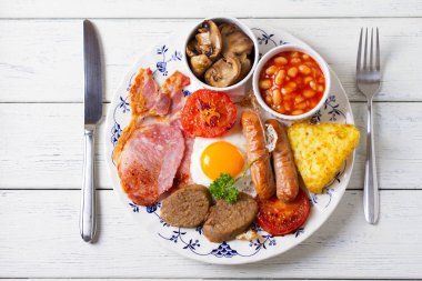 Sosis, domuz pastırması, puding, yumurtanın sarısı, patates kızartması, fasulye ve domatesli tam İrlanda kahvaltısı. Yukarıdan bak, en iyi stüdyo çekimi.
