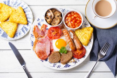 Sosis, domuz pastırması, puding, yumurtanın sarısı, patates kızartması, fasulye ve domatesli tam İrlanda kahvaltısı. Yukarıdan bak, en iyi stüdyo çekimi.