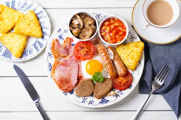 Sosis, domuz pastırması, puding, yumurtanın sarısı, patates kızartması, fasulye ve domatesli tam İrlanda kahvaltısı. Yukarıdan bak, en iyi stüdyo çekimi.