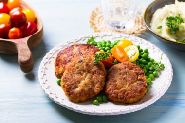 Beyaz tabakta sebzeli balık burgeri. Balık köftesi mi kek mi?