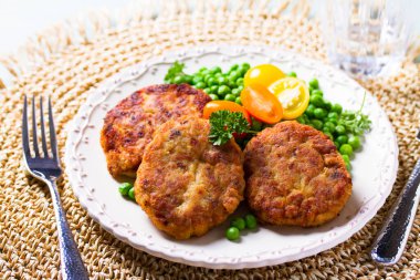 Beyaz tabakta sebzeli balık burgeri. Balık köftesi mi kek mi?