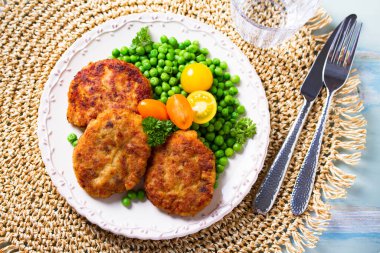 Beyaz tabakta sebzeli balık burgeri. Balık köftesi ya da kek. Yüksek açı görünümü