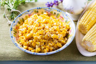 Lezzetli tereyağlı tatlı mısır kasesinde mavi ahşap arka planda