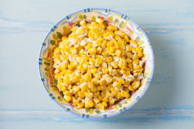 Lezzetli tereyağlı tatlı mısır kasesinde mavi ahşap arka planda. Yüksek açı görünümü