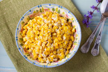 Lezzetli tereyağlı tatlı mısır kasesinde mavi ahşap arka planda. Yüksek açı görünümü