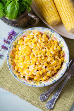Lezzetli tereyağlı tatlı mısır kasesinde mavi ahşap arka planda. Yüksek açı görünümü