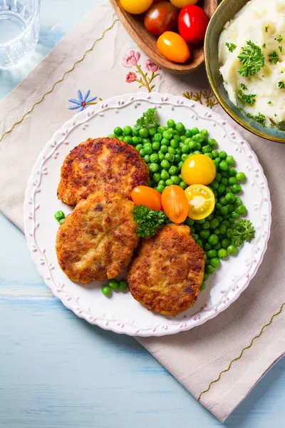 Beyaz tabakta sebzeli balık burgeri. Balık köftesi ya da kek. Yüksek açı görünümü