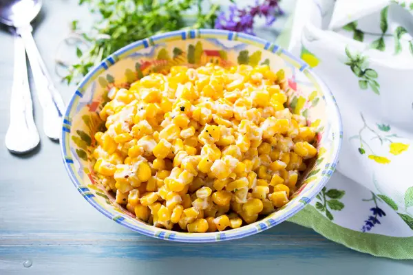 Lezzetli tereyağlı tatlı mısır kasesinde mavi ahşap arka planda