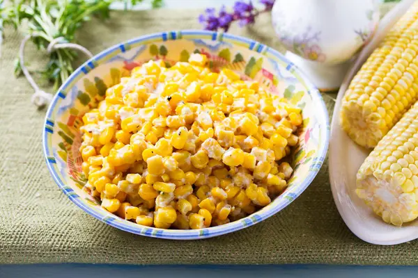 Lezzetli tereyağlı tatlı mısır kasesinde mavi ahşap arka planda