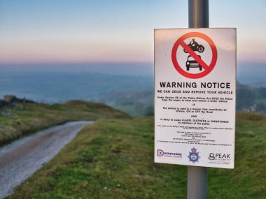 Derbyshire kırsalında yürüyüş yolunda bir uyarı işareti, alarm, sıkıntı ve rahatsızlığa yol açan araçların yakalanıp kaldırılabileceği yönünde uyarıda bulunuyor..