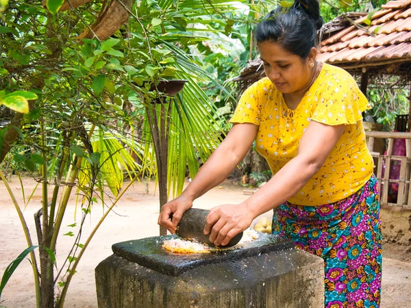 stock image A woman makes coconut sambol using a traditional stone grinder and grinding block outdoors in a village near Dambulla in central Sri Lanka.