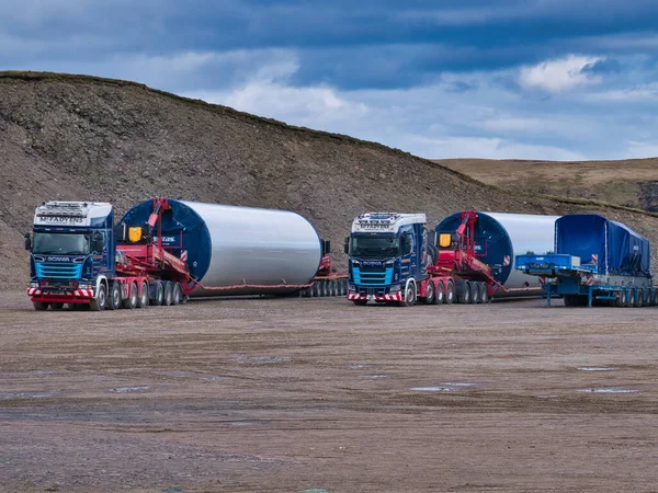 等着把风力涡轮机支撑塔部分运到建筑工地的卡车 在英国设得兰建造维京风力发电场的工作正在进行 图库图片