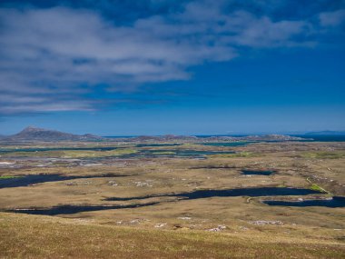 İskoçya 'nın Outer Hebrides kentindeki Doğu Benbecula kıyısı Kuzey Uist adasına bakıyor. Skye Adası sağda, en uzak mesafede görünüyor. Rueval tepesinden alındı..
