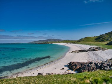 İskoçya 'nın Eriskay Adası' ndaki Traigh Leis 'in beyaz kum ve turkuaz suları. Yazın güneşli bir sabahta mavi gökyüzü ve ışık bulutuyla çekildi..