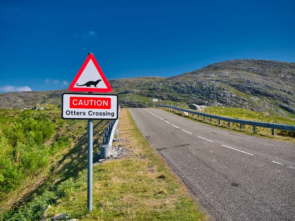 Road signs warning that otters may be crossing the road ahead. Taken at the bridge to the island of Scalpay in the Outer Hebrides, Scotland, UK on a sunny day with a blue sky