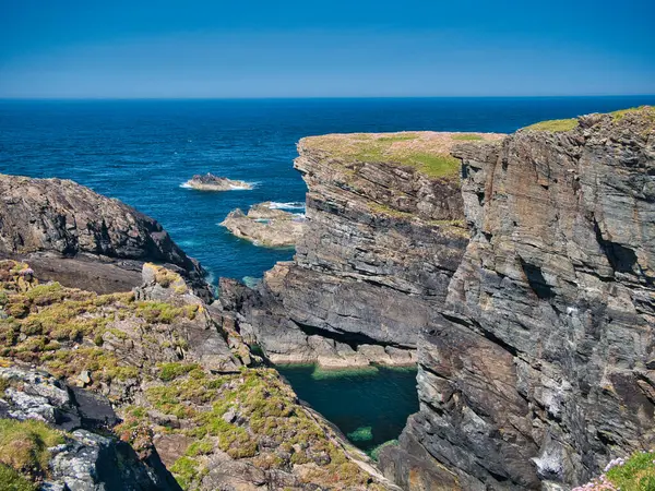 位于英国苏格兰外赫布里底群岛刘易斯岛的岩石 崎岖的大西洋海岸的海岸悬崖中暴露的岩层 在夏天阳光灿烂的日子拍的 图库图片